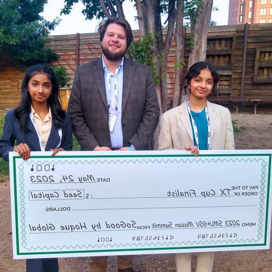 Three people posing with a giant novelty check.